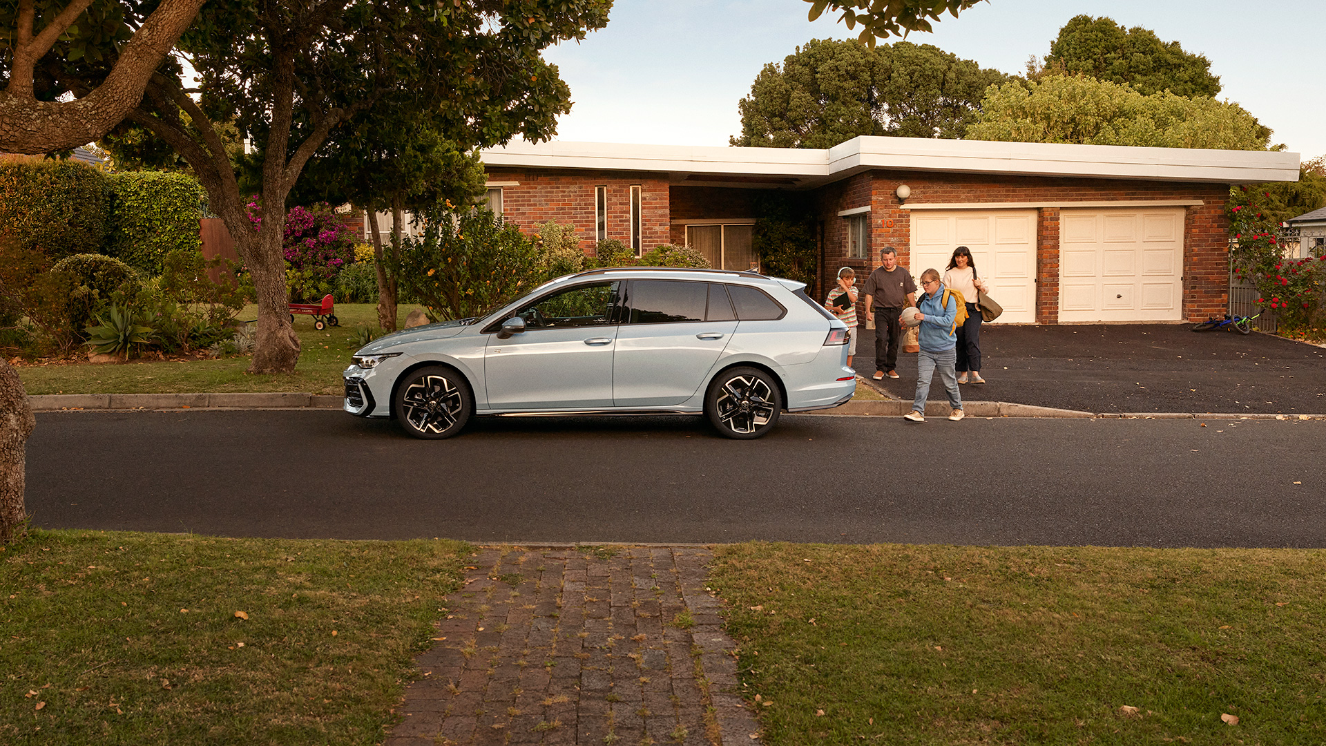 En Vit Volkswagen Golf Sportscombi Star Parkerad Utanfor En Villa. Familjen Ar Pa Garageuppfarten